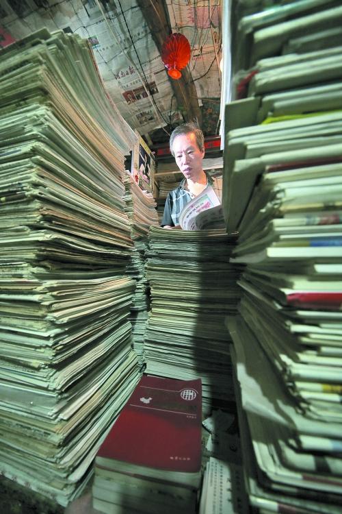 王曉民坐在寫字桌前，被報紙淹沒。