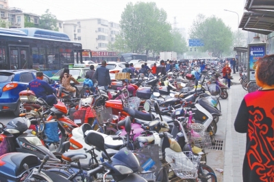 省人民醫院北門，路邊的公交站牌處停滿非機動車，上、下客只能在快車道上。