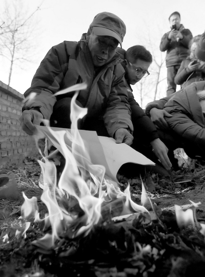 李三仁在兒子墳前焚燒再審無罪判決文書的復印件。新華社發