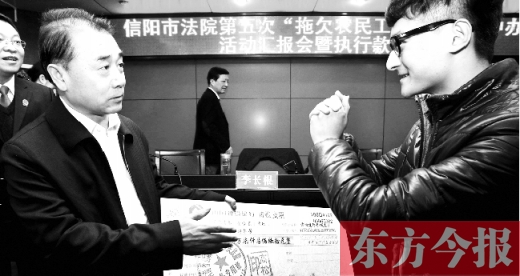 張立勇將依法執行回來的農民工工資發放給案件當事人游昌華，游昌華施以中國傳統作揖禮答謝