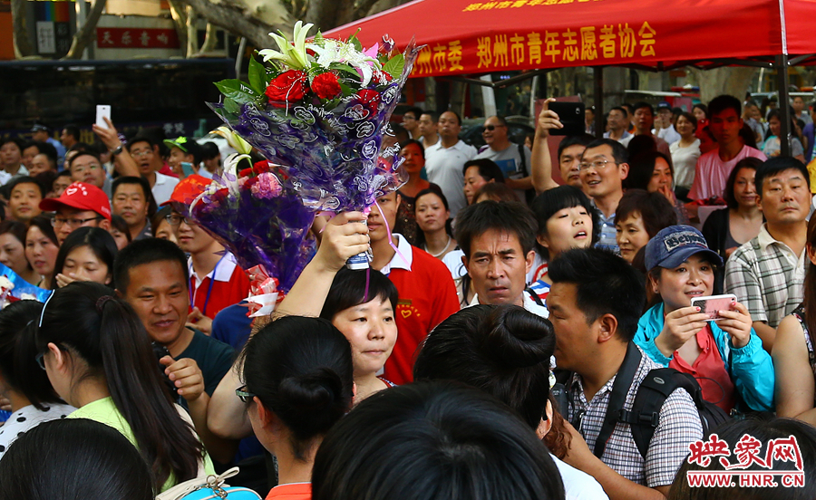 一位家長高舉鮮花在人群中尋找自己的孩子 一位家長高舉鮮花在人群中尋找自己的孩子