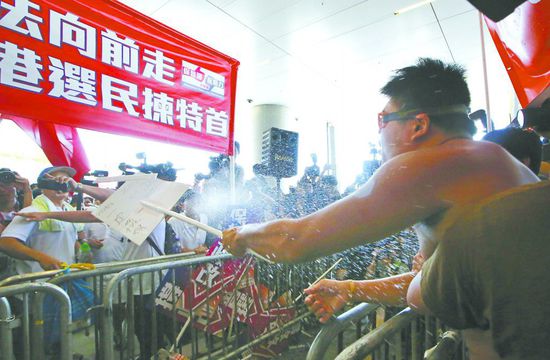 17日，在香港立法會(huì)外，一名反對(duì)政改的男子向支持派人群投擲標(biāo)牌。
