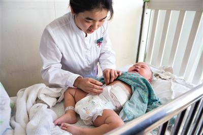 昨日,北京兒童醫院,護士為即將出院的被扎鋼針女嬰檢查傷口恢復情況。記者 高瑋 攝 昨日,北京兒童醫院,護士為即將出院的被扎鋼針女嬰檢查傷口恢復情況。記者 高瑋 攝